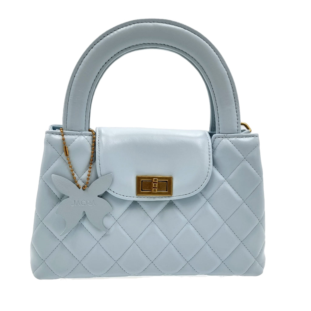 Light blue real leather quilted handbag with a decorative bow on a white background