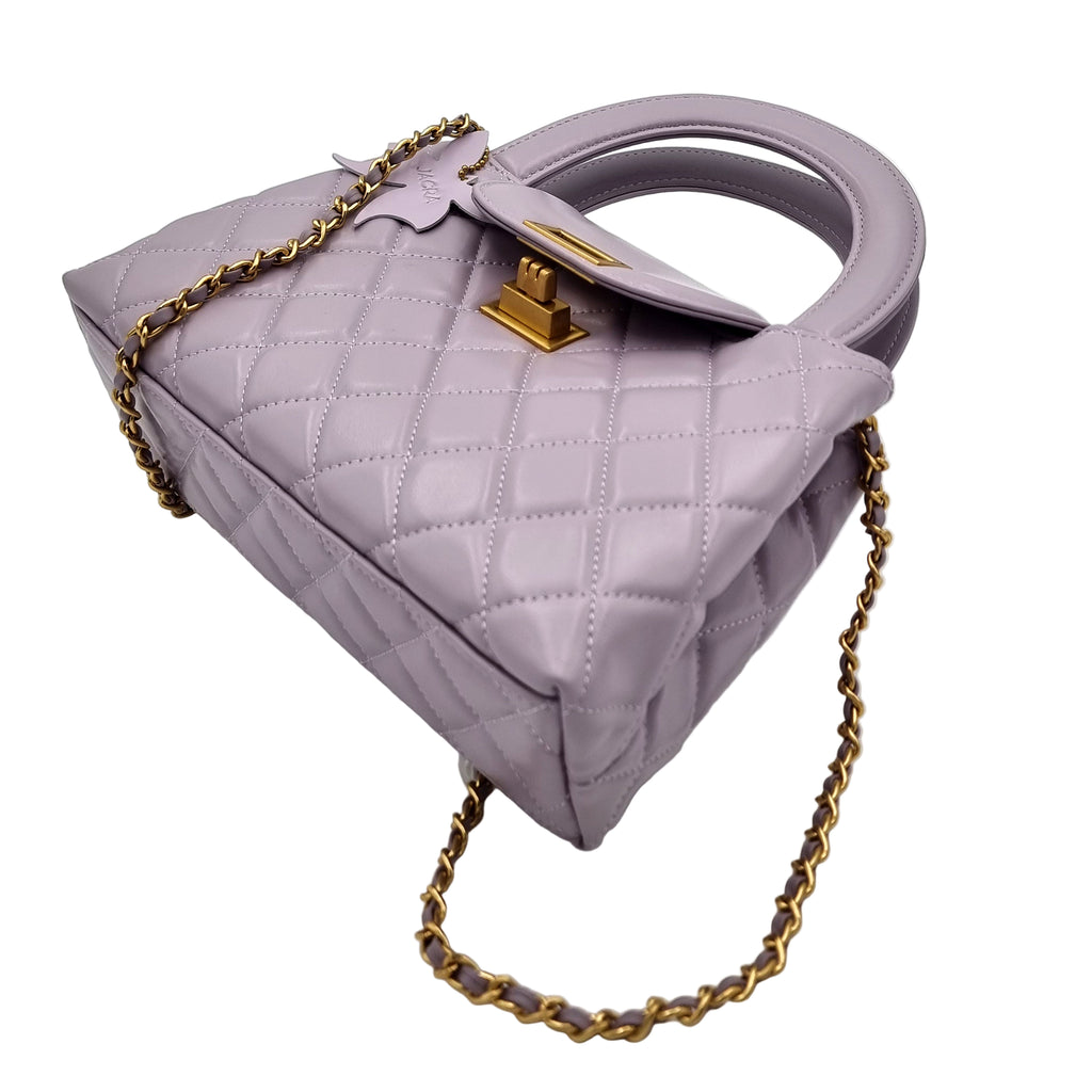 Purple quilted real leather handbag with gold chain and clasp on a white background