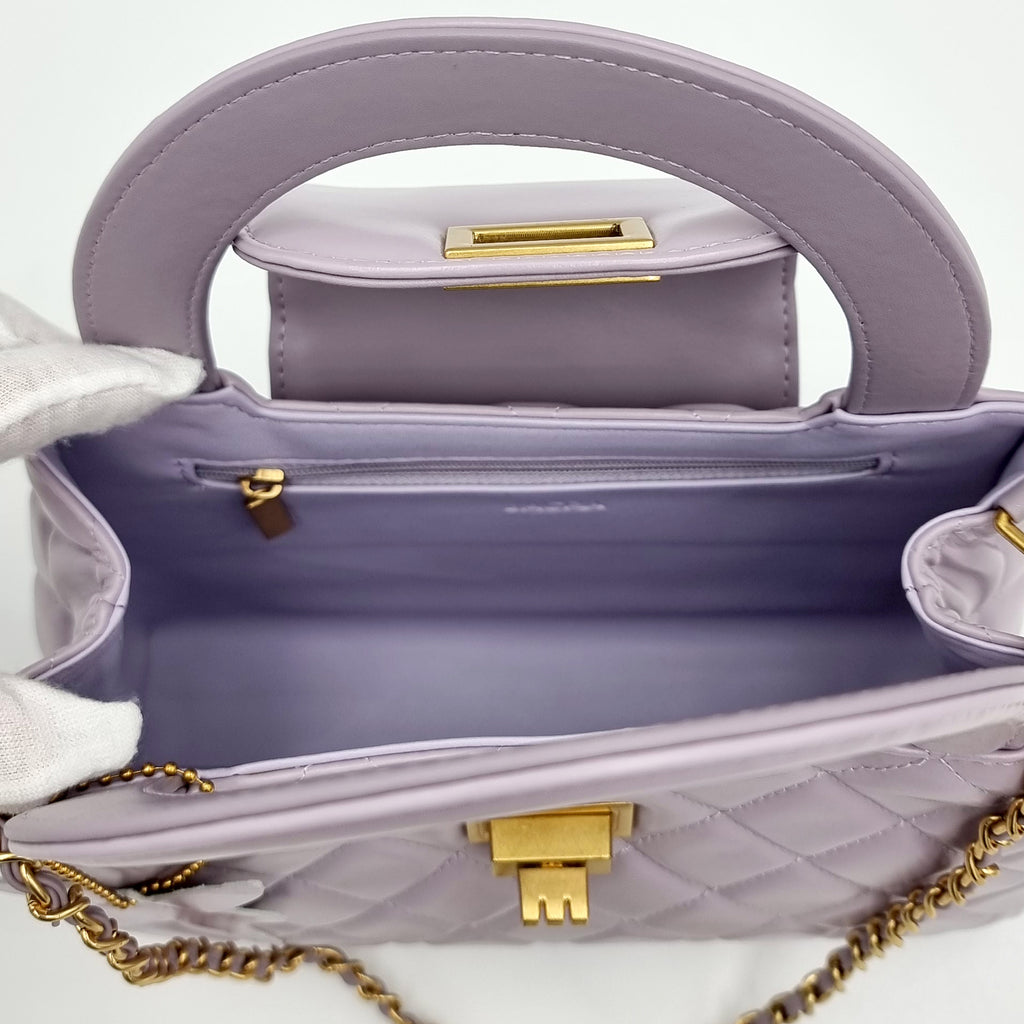 Lilac real leather handbag with gold accents on a light gray background
