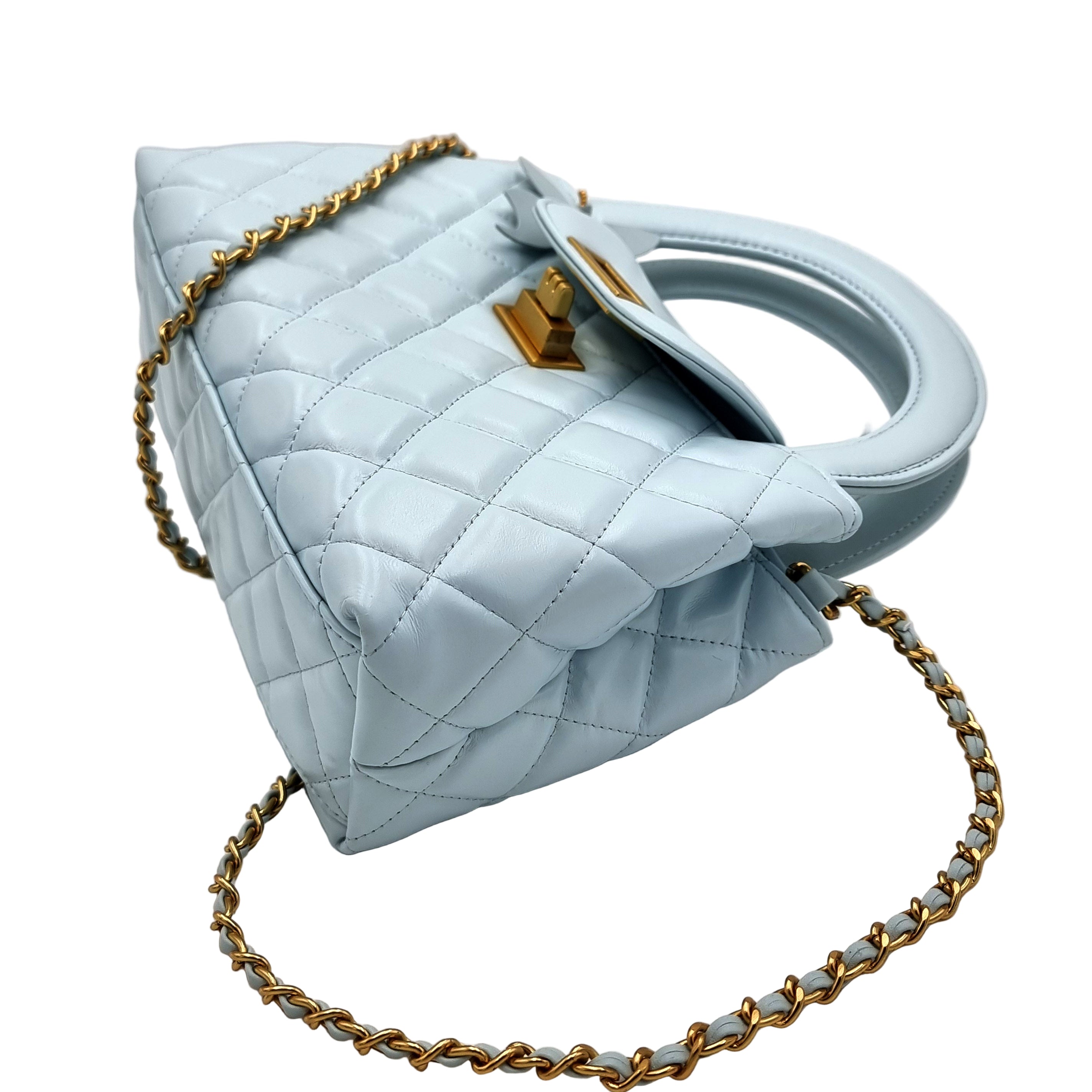 Powder blue quilted handbag with gold chain on a white background