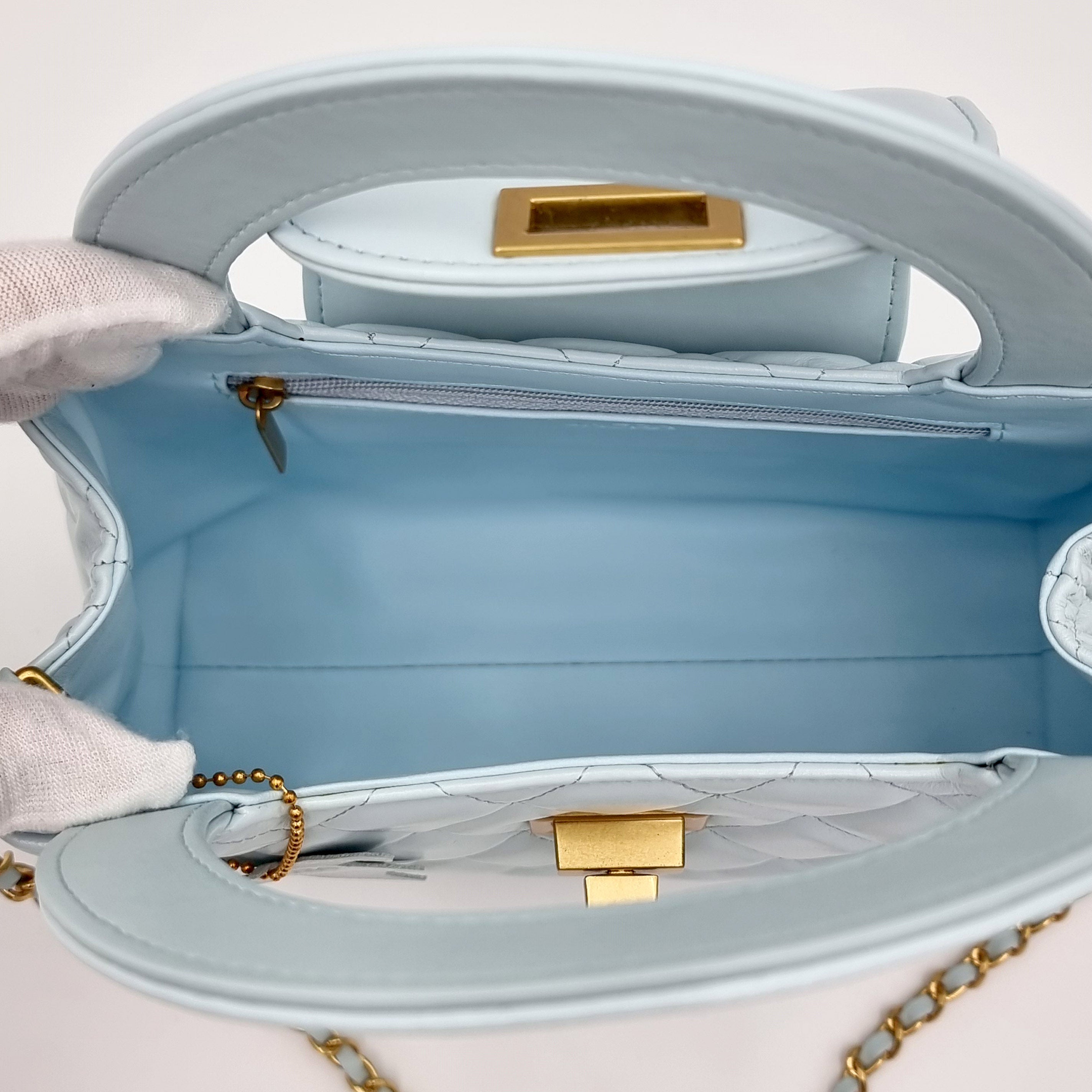 Light blue real leather handbag with gold hardware on a light background